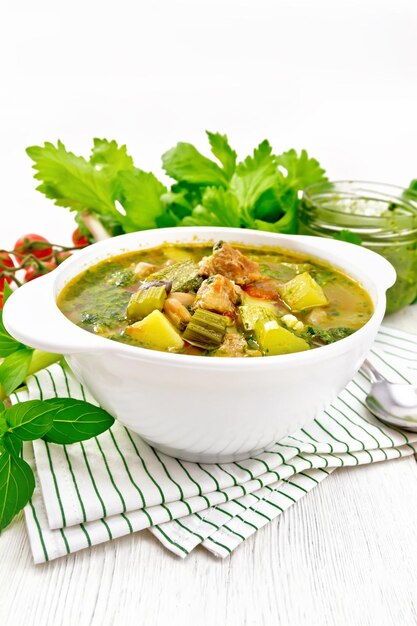 Soup with pisto sauce in bowl on light wooden board