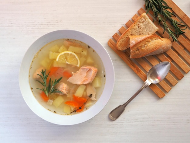 Soup with salmon vegetables rosemary and a slice of lemon