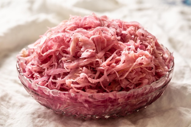 Sour cabbage served in a glass bowl on a rustic tablecloth