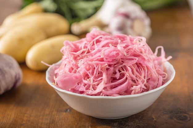 Sour cabbage with potatoes and garlic on wooden table.