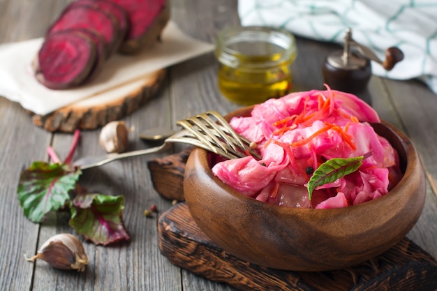 Sour cabbage with with beets and carrots in a  bamboo bowl on old wooden table. Rustic style. Selective focus.