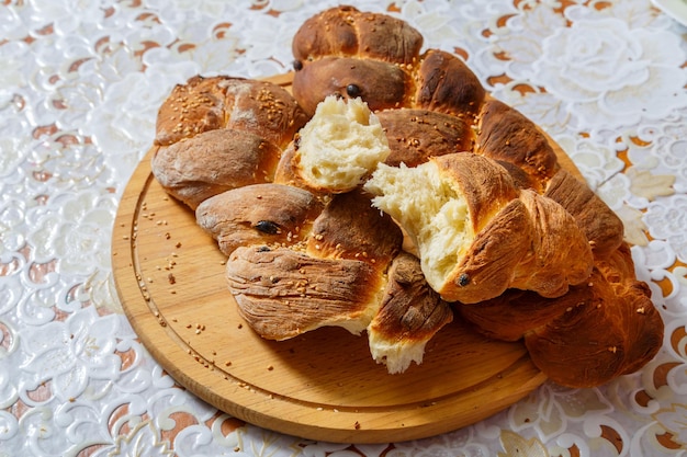 Sour challahs on a wooden round board on a white tablecloth