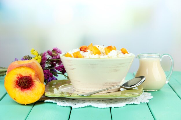 Sour cheese and pieces of fresh peach on wooden table on defocused nature