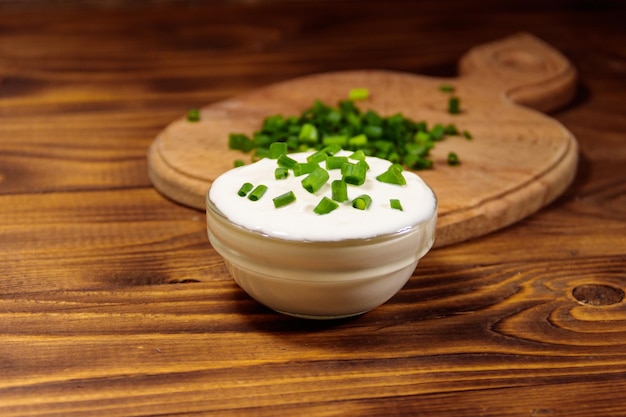 Sour cream and green onion on wooden table