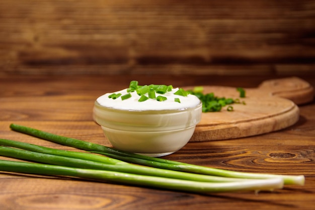 Sour cream and green onion on wooden table