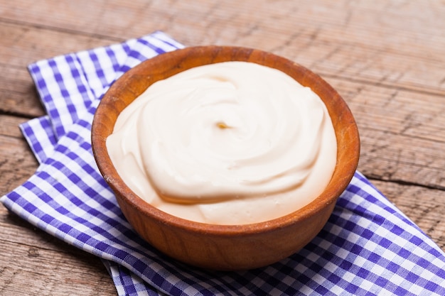 Sour cream in a wooden bowl. Farm organic product