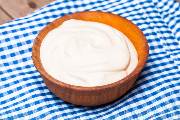 Sour cream in a wooden bowl. Farm organic product