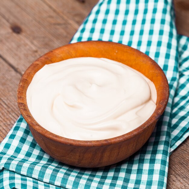 sour cream in a wooden bowl. farm organic product