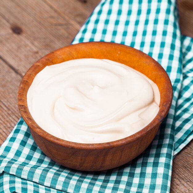 Sour cream in a wooden bowl. Farm organic product