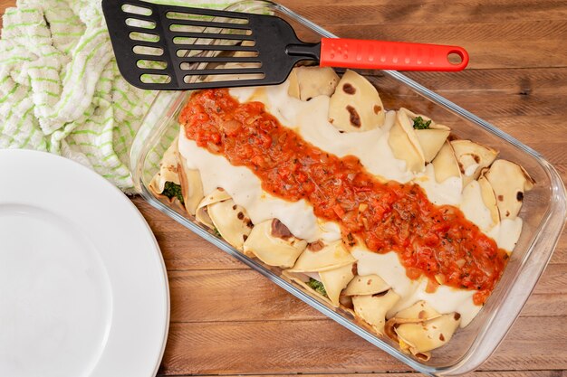 Foto fonte di cannelloni di spinaci fatti in casa con besciamella e filetto. concetto di cucina casalinga, cibo sano.