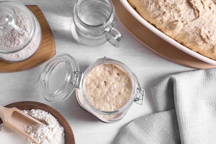 Photo sourdough starter in glass jar flour dough and water on light table flat lay