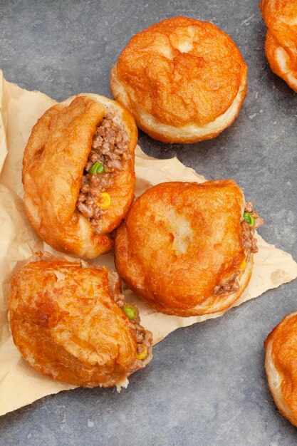 South african vetkoek deep fried savory dough filled with saucy savory mince on mottled grey background with copy space