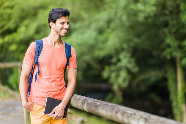 South asian 40s male hiking with a backpack in Asturias green countryside with a diary in spain