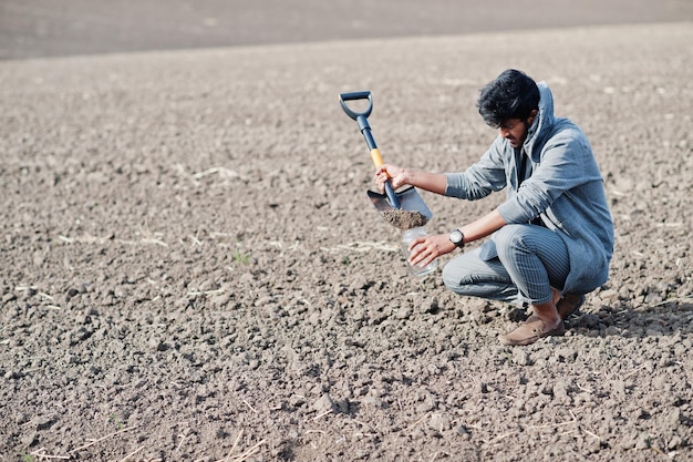 South asian agronomist farmer with shovel inspecting black soil Agriculture production concept