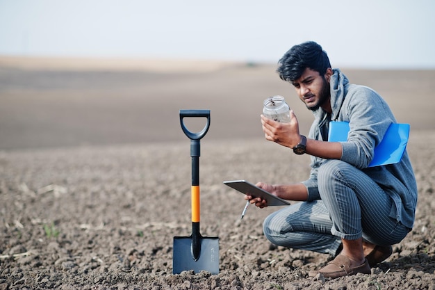 South asian agronomist farmer with shovel inspecting black soil Agriculture production concept