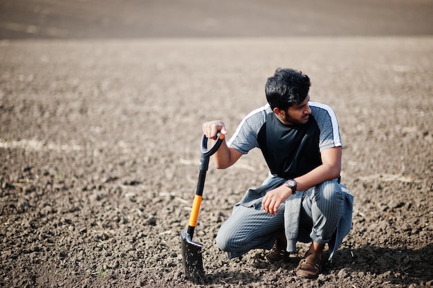 South asian agronomist farmer with shovel inspecting black soil Agriculture production concept