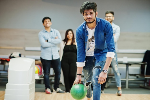 South asian man in jeans shirt standing at bowling alley and throw ball