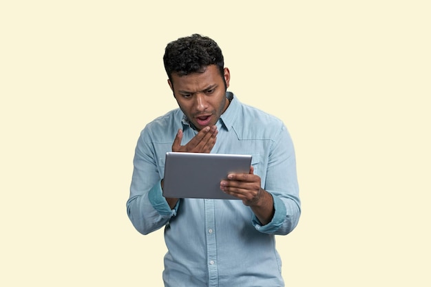 South asian man with expression of bewilderment and surprise holding tablet pc puzzled indian guy on