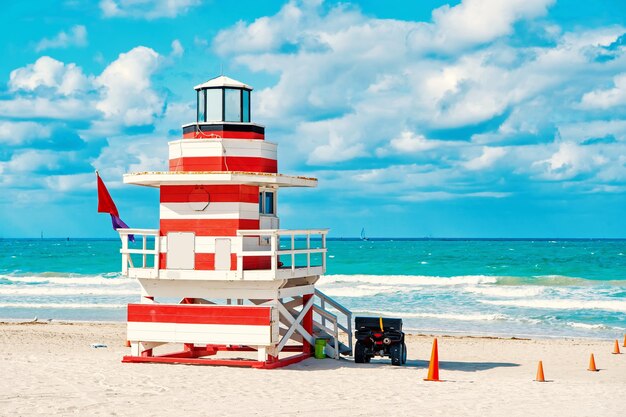 South Beach, Miami, Florida, lifeguard house in a colorful Art Deco red and whhite style on cloudy blue sky and Atlantic Ocean in background, world famous travel location