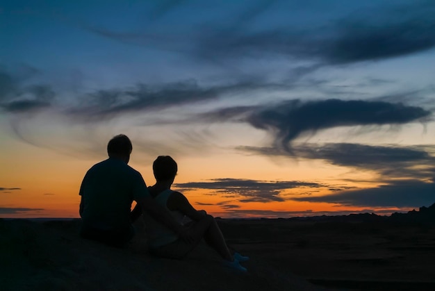 Foto badlands del sud dakota. coppia romantica stagliano contro un bel tramonto sulla cima della montagna