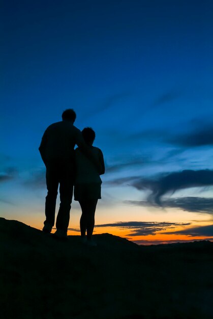 サウスダコタ州バッドランズ。山の頂上に美しい夕日を背景にシルエットのロマンチックなカップル