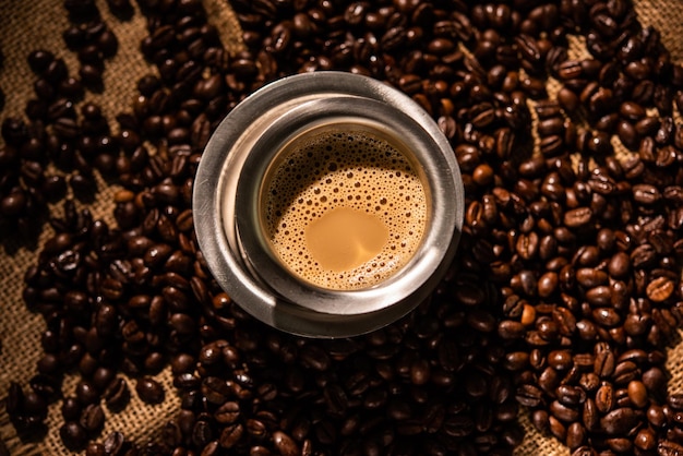 South indian filter coffee served in a traditional tumbler or\
cup over roasted raw beans