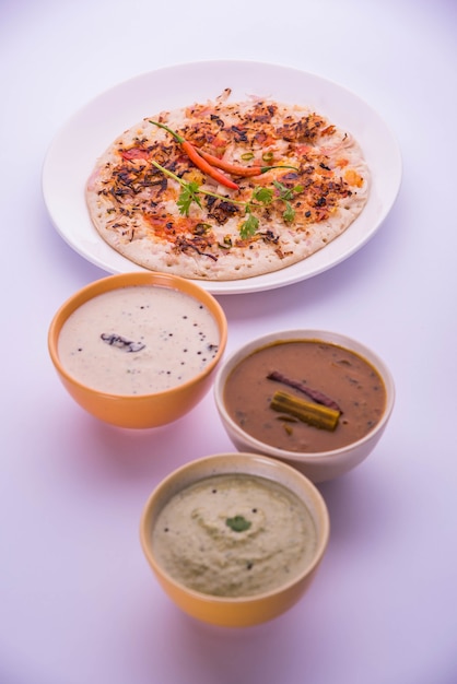 South Indian Food Uttapam or ooththappam or Uthappa is a dosa-like dish made by cooking ingredients in a batter, served with coconut chutney, green chutney and sambar