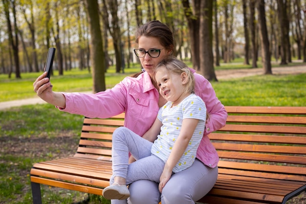 Сувенирные фотографии матери и дочери, сделанные на смартфон в городском парке