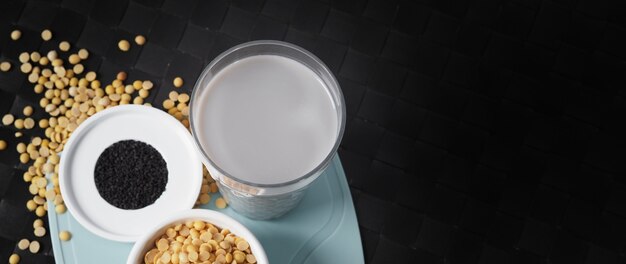 soy milk blended with black sesame in clear glass on black plate mat black sesame seed and soy bean