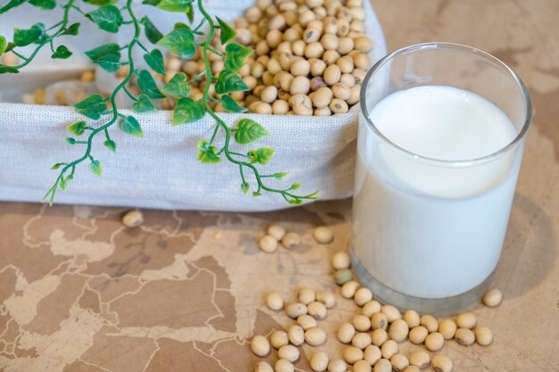 ガラスの豆乳とバケツの大豆。自然健康概念。