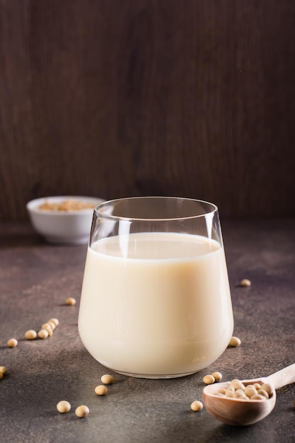 Soy milk in a glass and soybeans in a bowl on the table Lactose free drink Vertical view