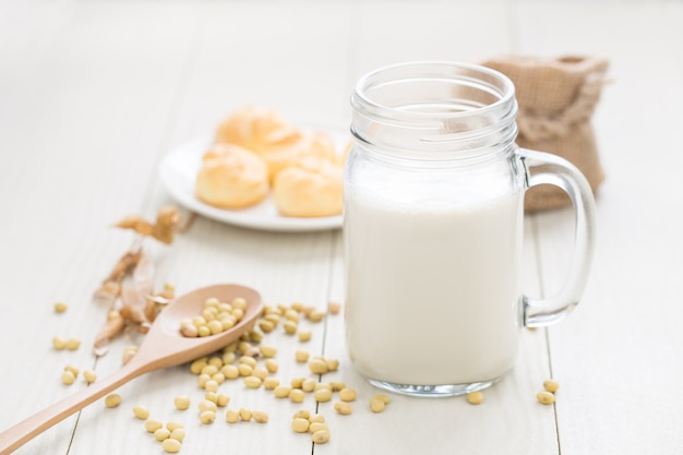 Soy milk in a glass , soybeans on a white table