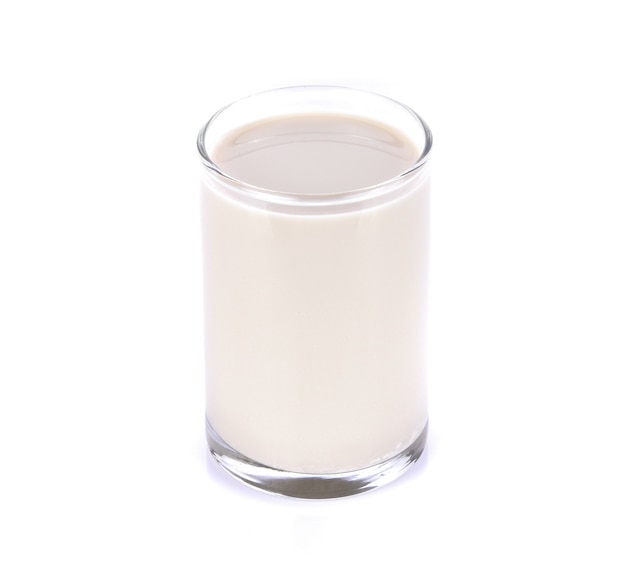 Soy milk in a glass on a white surface