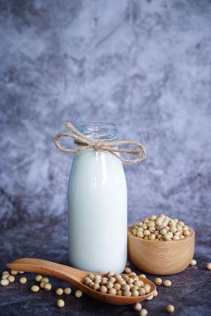 Latte di soia in un bicchiere con semi di soia in tazza di legno