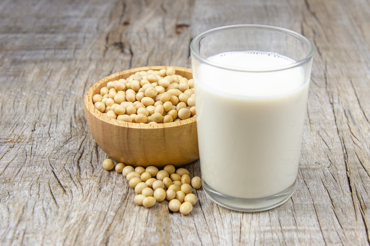 Photo soy milk with soybean on wooden background.