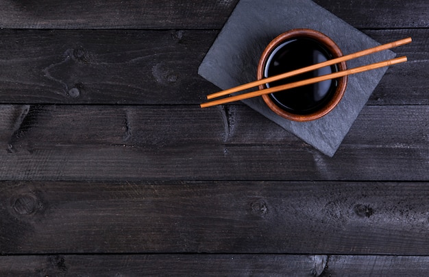 Photo soy sauce, chopsticks on black stone, top view