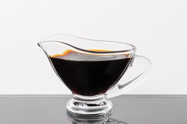 Soy sauce in a glass gravy boat on a black table