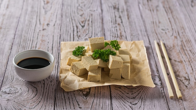 Фото Соевый соус с кусочками тофу на бумаге с петрушкой