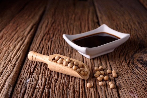 Foto salsa di soia con il fagiolo di soia su fondo di legno.