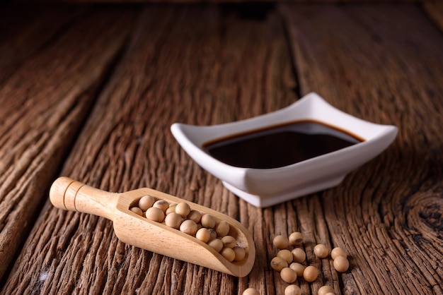 Photo soy sauce with soy bean on wooden background.