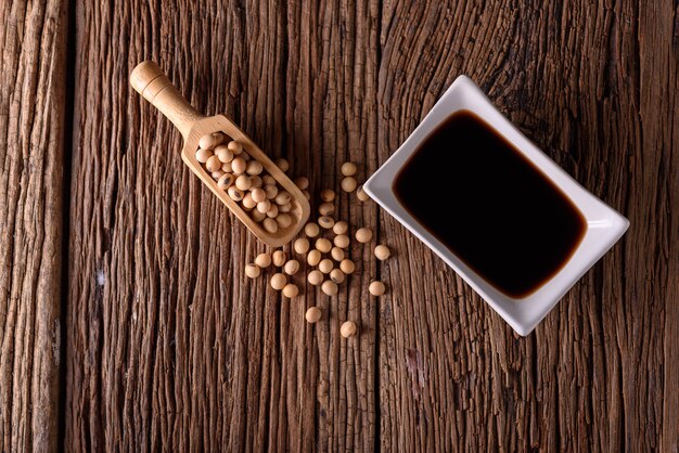 Soy Sauce with soy bean on wooden background.