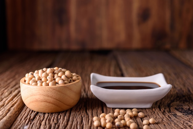 Photo soy sauce with soy bean on wooden background.