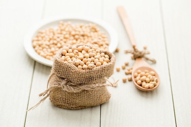 Soya beans in a sack on a wooden table