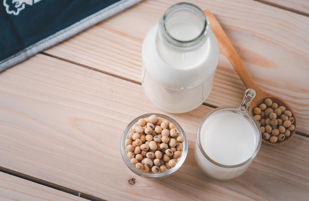 Soybean seeds in glass bowl And milk in glass bottle on wooden table