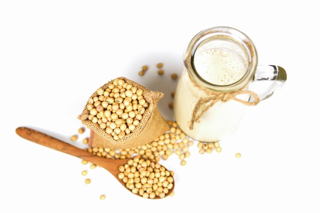 Soybean on wooden spoon and dried soy beans in the sack on white