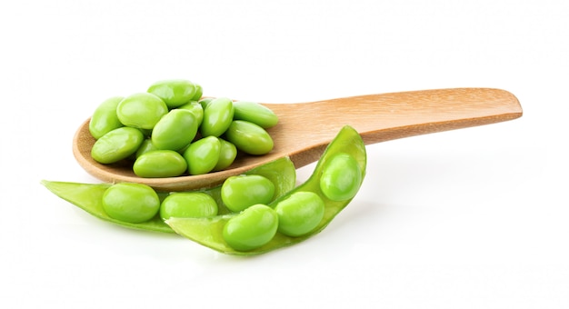 Soybeans in wood spoon on white