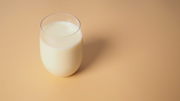 Soymilk in glass on yellow background.