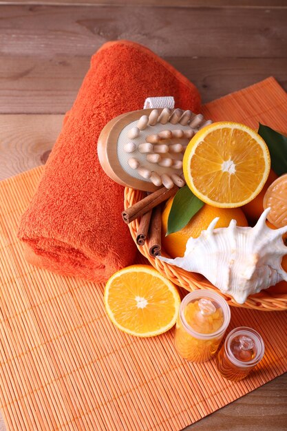 Photo spa accessories in wicker basket with rolled towel on color bamboo mat on wooden background