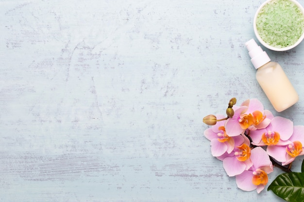 Spa aromatherapy background, flat lay of various beauty care products decorated with simple orchid flowers.