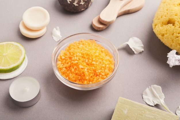 Sfondo della stazione termale. sale marino naturale con olio essenziale di limone e vari prodotti di cosmetologia sul tavolo grigio. salone o casa auto corpo e pelle